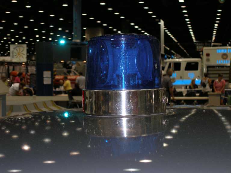 Blue rotating police beacon with chrome base on a car roof at an indoor show