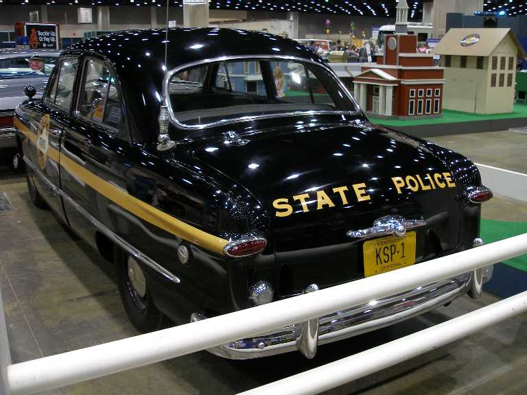Black 1949 Ford sedan restored as Kentucky State Police car, rear view at indoor show