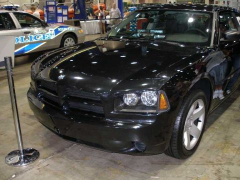 1998 Ford Crown Victoria - Black Dodge Charger sedan photographed from a front three-quarter angle at an indoor show, with a chrome stanchion in front and a Louisvill…