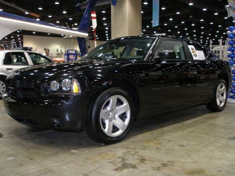 1998 Ford Crown Victoria - A black Dodge Charger sedan photographed from the front three-quarter angle at an indoor auto show, showing silver five-spoke wheels and a…