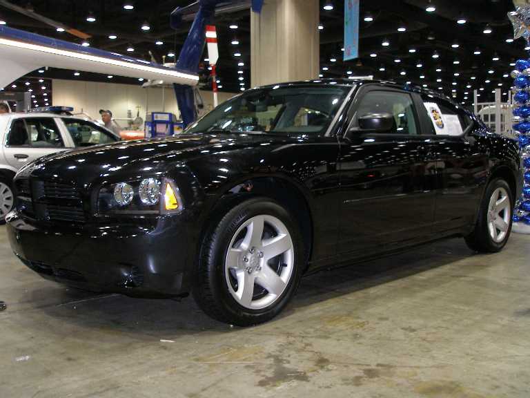 Black Dodge Charger sedan at indoor auto show, front three-quarter view