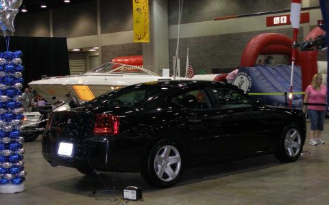 1998 Ford Crown Victoria - A black four-door sedan is displayed at an indoor show, viewed from the rear three-quarter angle, with alloy wheels and a small placard und…