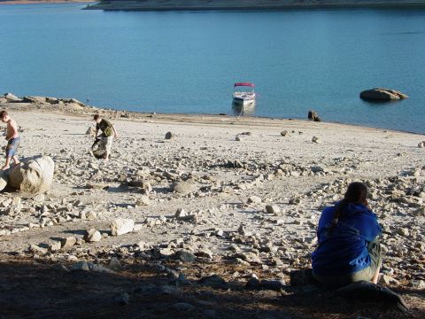 1986 Ford Bronco - A boat is moored near the shore of a lake, with several people on the rocky beach.