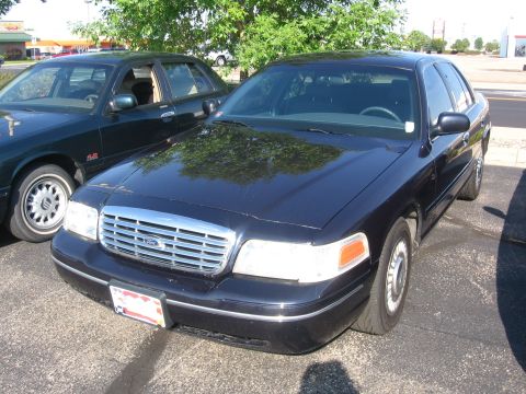 1999 Ford Crown Victoria - A black Ford Crown Victoria is parked in a lot, with another dark-colored sedan beside it.