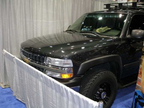 1998 Ford Crown Victoria - A black Chevrolet full-size SUV (Tahoe/Suburban) shown from the front three-quarter angle at an indoor show, with a roof rack, black-painte…