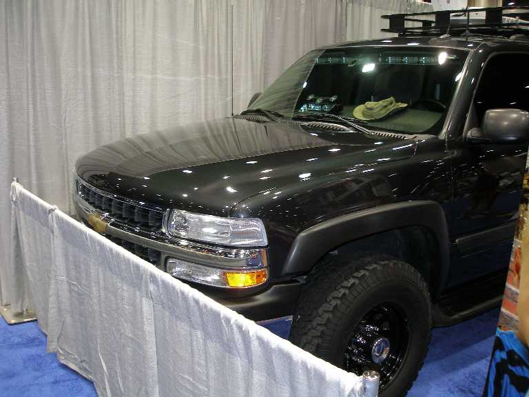 Black Chevrolet full-size SUV, front 3/4 view, at indoor display behind white barrier