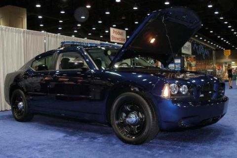 1998 Ford Crown Victoria - A dark blue Dodge Charger sedan displayed at an indoor auto show with its hood open, fitted with black steel police-style wheels and a roof…