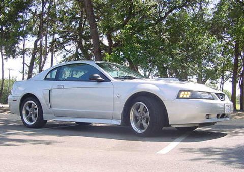 1999 Ford Mustang - A silver coupe is parked on an asphalt surface with trees in the background.