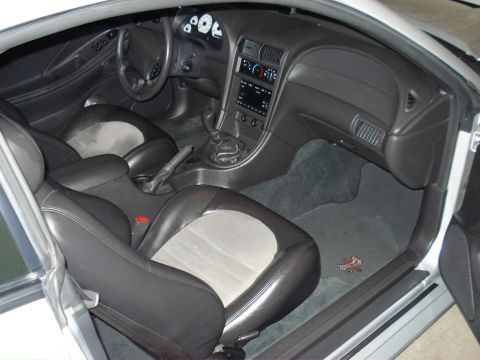 1998 Ford Taurus - The interior of this vehicle features two-tone seats, a manual transmission, and a floor mat with a distinctive red emblem.