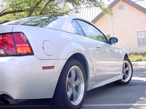 1999 Ford Mustang - Silver 1999 Ford Mustang coupe parked outdoors with a building in the background.