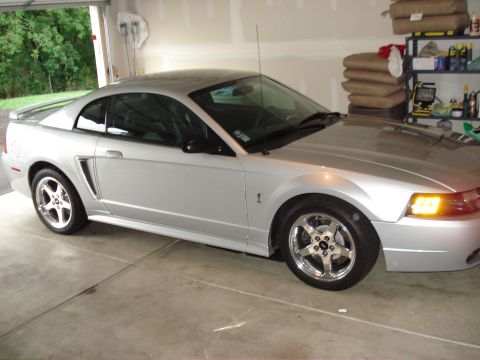 1998 Ford Taurus - This silver Ford Mustang SVT Cobra is parked in a garage, showing its side profile and custom wheels.