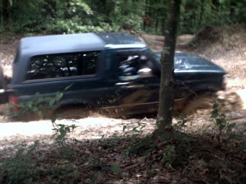 1996 Ford Bronco - This Ford Bronco is navigating a muddy path in a wooded area.