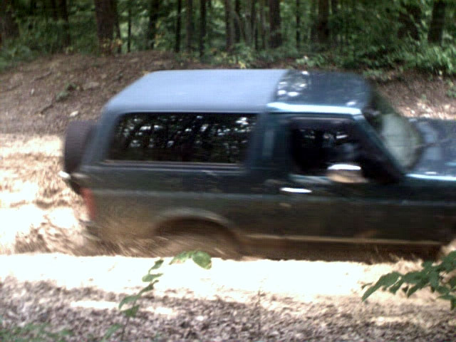 1996 Ford Bronco driving through mud on a dirt trail