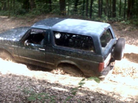 1996 Ford Bronco - A 1996 Ford Bronco navigates a muddy trail, with its rear spare tire mounted externally.