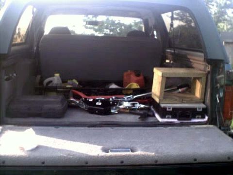 1996 Ford Bronco - The cargo area of an SUV is filled with various items, including tools and a wooden crate.