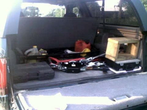1996 Ford Bronco - The cargo area of an SUV is filled with various items, including tools and a red gas can.