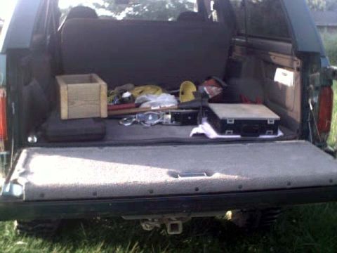 1996 Ford Bronco - The cargo area of a 1996 Ford Bronco contains various items including a wooden crate and a black case.