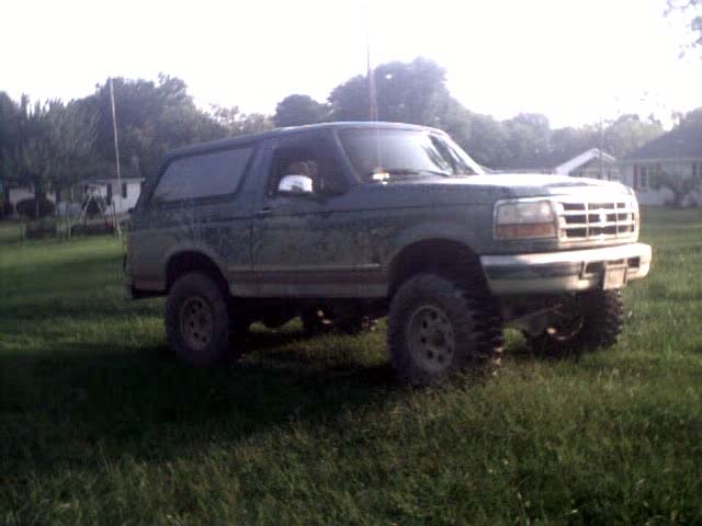 Green Ford Bronco parked in grassy yard, front quarter view