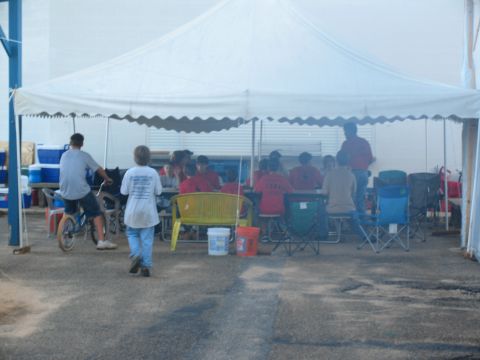 1995 Ford C-350 (Centurion Conversions) - A gathering of people under a large tent, with some seated at tables and others standing around.