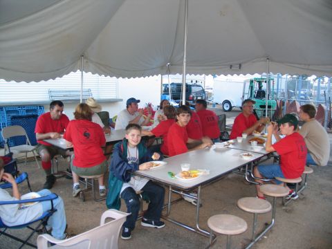 1995 Ford C-350 (Centurion Conversions) - Group eating outdoors under a tent, with a forklift and trailer in the background.