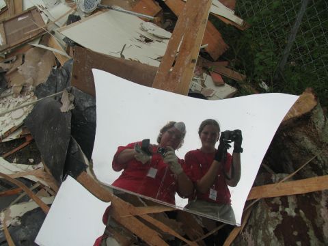 1995 Ford C-350 (Centurion Conversions) - Two individuals capture a moment amidst the wreckage, reflected in a shattered mirror.