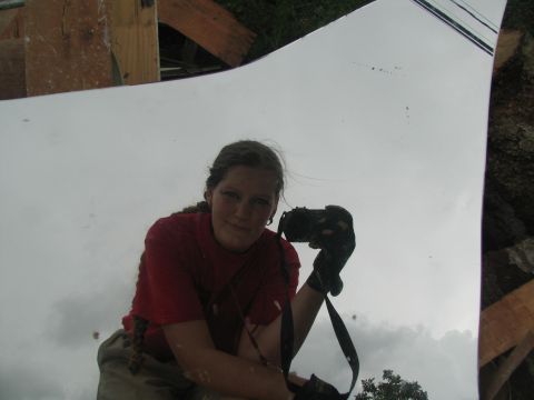 1995 Ford C-350 (Centurion Conversions) - A woman takes a selfie in a reflective surface, with debris and clouds visible in the background.