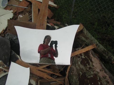 1995 Ford C-350 (Centurion Conversions) - A woman captures her reflection while holding a camera amidst the wreckage of a destroyed structure.