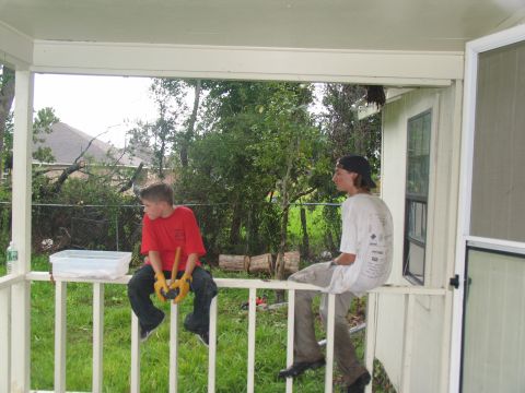 1995 Ford C-350 (Centurion Conversions) - Two young males sit on a porch railing, with debris and downed trees visible in the background.