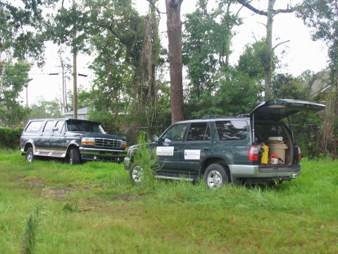 1995 Ford C-350 (Centurion Conversions) - Two vehicles, a Ford F-Series truck and an SUV, are parked in a grassy area with trees in the background.
