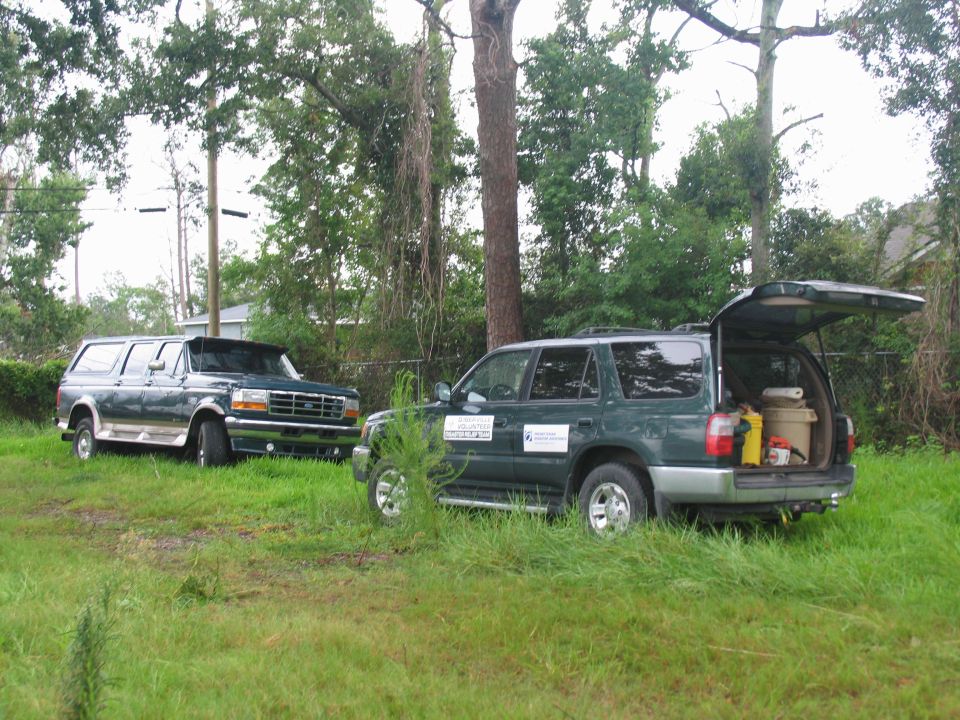 Dark green Ford F-Series truck with chrome grille and trim, parked next to a dark green SUV with its rear hatch open