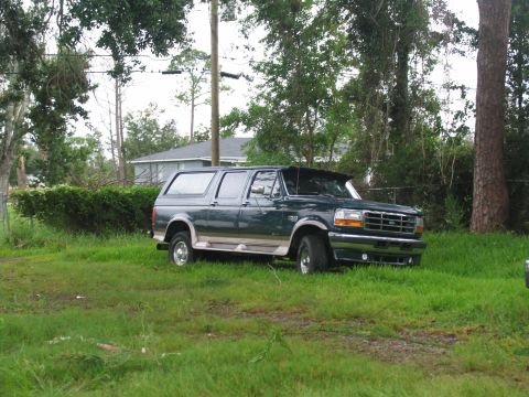 1995 Ford C-350 (Centurion Conversions) - This 1995 Ford C-350 Centurion conversion SUV is seen parked in a grassy area with trees and a house in the background.