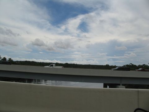 1995 Ford C-350 (Centurion Conversions) - Vehicles travel on a highway overpass under a cloudy sky.