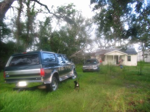 1995 Ford C-350 (Centurion Conversions) - A dark green Ford Bronco SUV is parked in a grassy yard with a small house and another vehicle in the background.