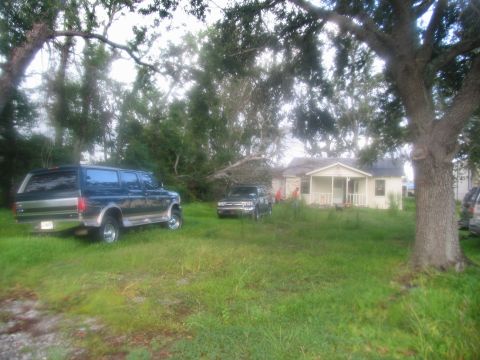 1995 Ford C-350 (Centurion Conversions) - A dark blue SUV with chrome trim is parked in a grassy yard next to a small house.