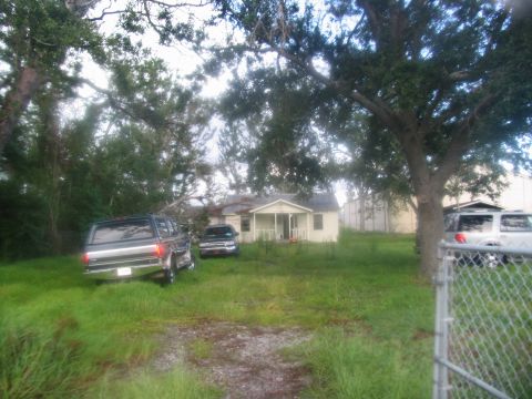 1995 Ford C-350 (Centurion Conversions) - Multiple vehicles are parked in front of a damaged house, possibly after a natural disaster.