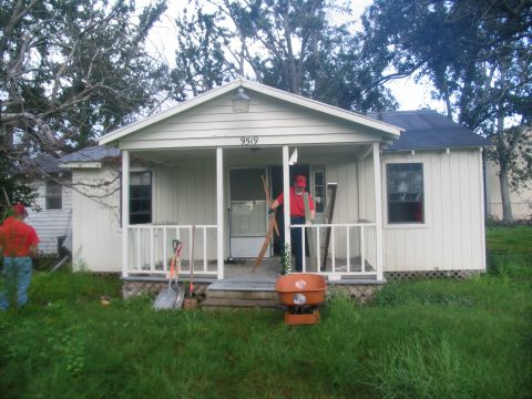 1995 Ford C-350 (Centurion Conversions) - Two men are working outside a house, with tools and a cement mixer visible on the porch.