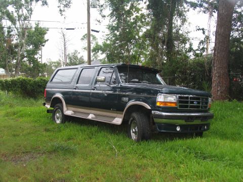 1995 Ford C-350 (Centurion Conversions) - A dark green Ford SUV with tan trim is parked on a grassy area.