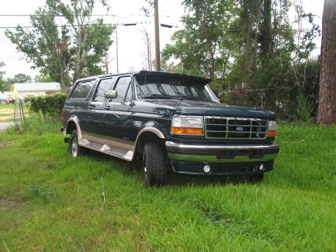 1995 Ford C-350 (Centurion Conversions) - This dark green SUV with tan trim is parked on a grassy area, seen from a 3/4 front angle. The vehicle appears to be a mid-1990s model.