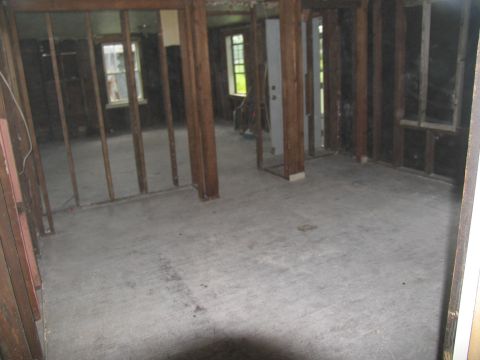 1995 Ford C-350 (Centurion Conversions) - The interior of a building shows exposed wooden studs and a concrete floor, indicating renovation or damage.