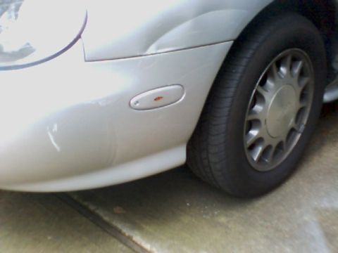 1998 Ford Taurus - Close-up of the front fender and wheel of a 1998 Ford Taurus.