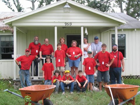 1995 Ford C-350 (Centurion Conversions) - A group of volunteers pose for a photo in front of a house, ready for a day of work.