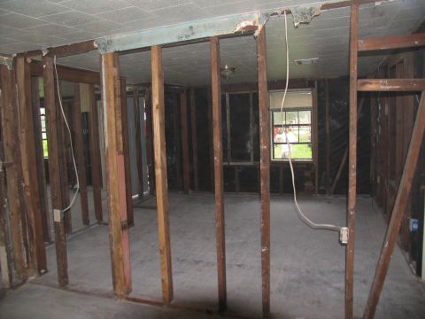 1995 Ford C-350 (Centurion Conversions) - The interior of a room shows significant damage with exposed wooden studs and missing wall coverings.