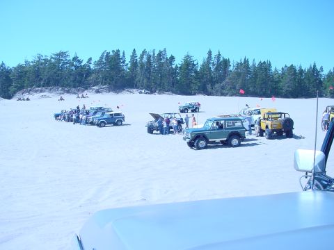 1979 Ford Bronco - A group of off-road vehicles gathered on a sandy terrain under a clear blue sky.