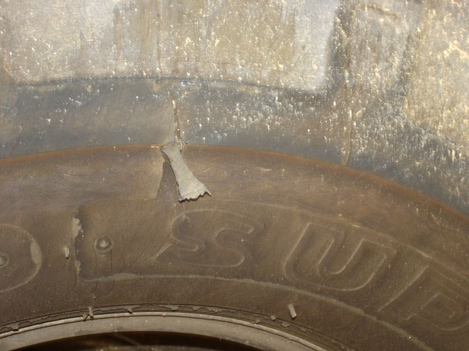 Close-up of tire sidewall with peeling rubber flap and partial 'SUP' lettering visible