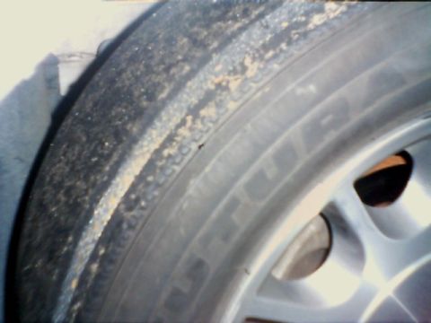 1998 Ford Taurus - A close-up view of a car's tire and wheel, showing dirt accumulation on the tire's sidewall.