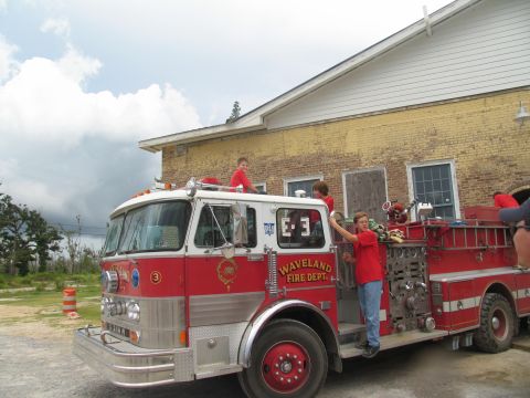 1995 Ford C-350 (Centurion Conversions) - A group of children are gathered around a fire truck outside a yellow brick building.