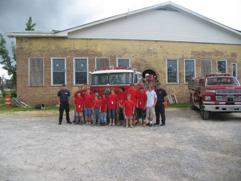 1995 Ford C-350 (Centurion Conversions) - A group of people, likely firefighters or trainees, stand with two fire trucks in front of a building.