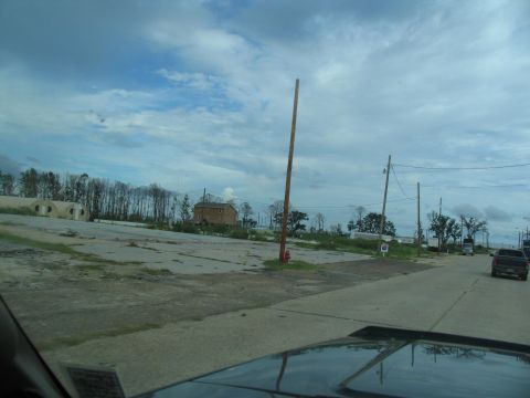 1995 Ford C-350 (Centurion Conversions) - A street scene shows the aftermath of a disaster with damaged structures and debris under a cloudy sky.