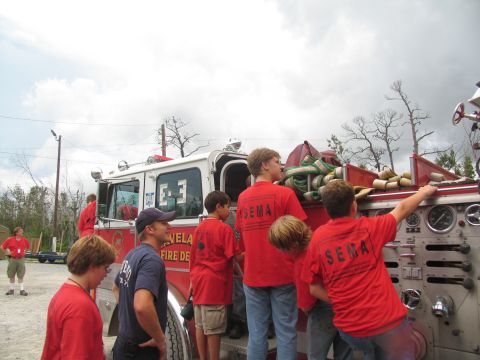 1995 Ford C-350 (Centurion Conversions) - A fire truck with 'VELA FIRE DEPT' visible is surrounded by individuals wearing red SEMA shirts.