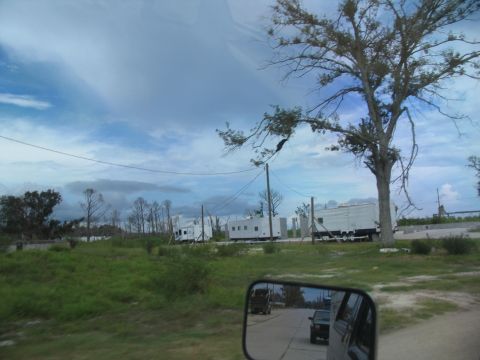 1995 Ford C-350 (Centurion Conversions) - Several white box trucks are lined up on a road, suggesting a scene of disaster relief or temporary housing in an affected area.